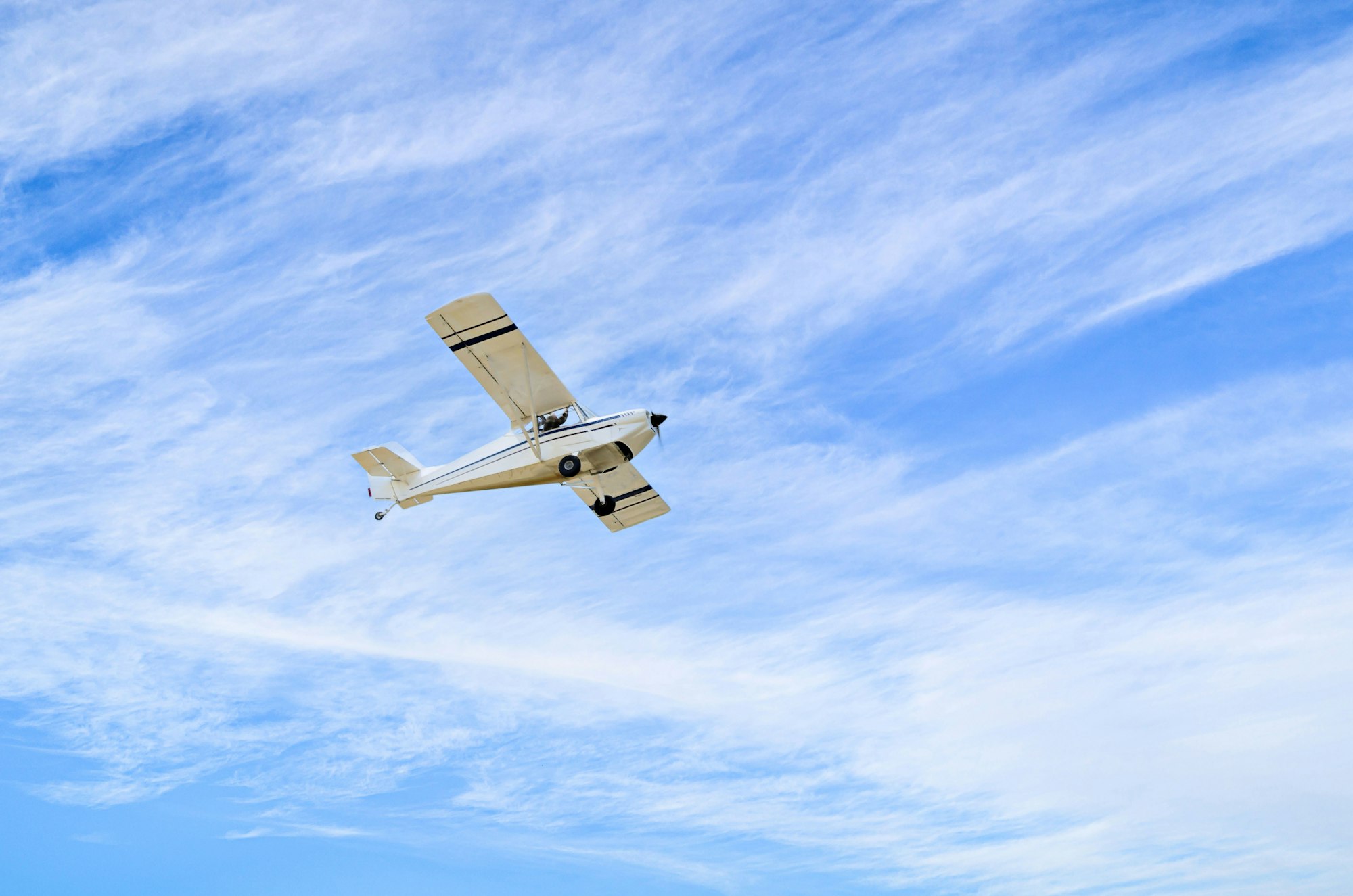 Single engine ultralight plane flying in the cloudy blue sky